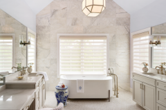 The spacious primary bathroom features lighting by Visual Comfort and a vanity stool covered in Schumacher fabric. The towels are Matouk and the fixtures are from Ferguson Kitchen and Bath. 