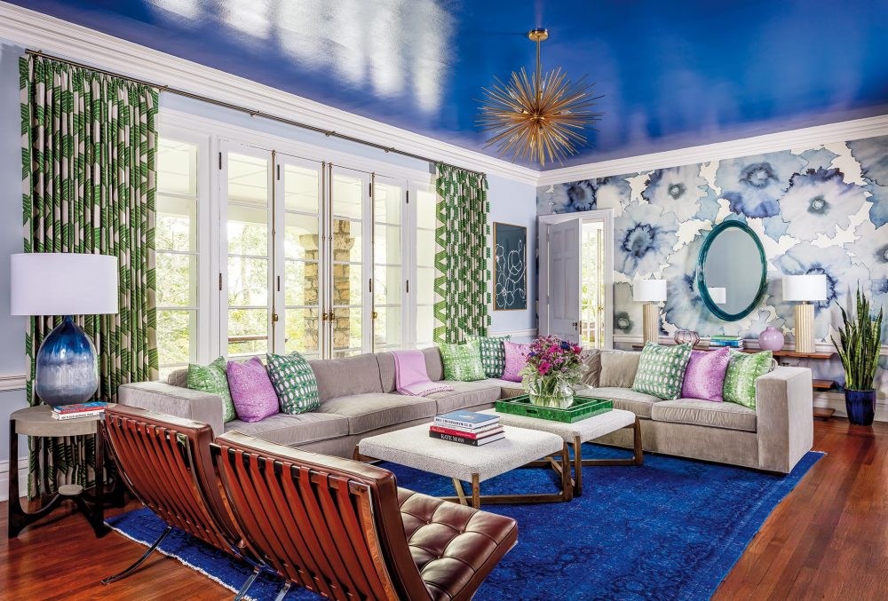 A blue lacquer from Benjamin Moore contrasts with wallpaper by Phillip Jeffries, drapery fabric by Zoffany and Kravet-covered ottomans in the living room. The Barcelona chairs are from Knoll.